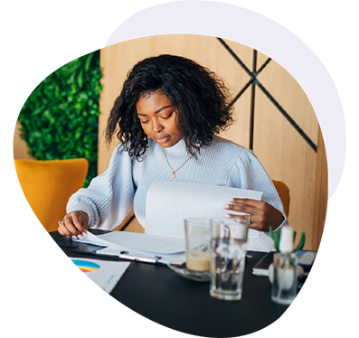 Woman looking over papers with coffee and water at her desk