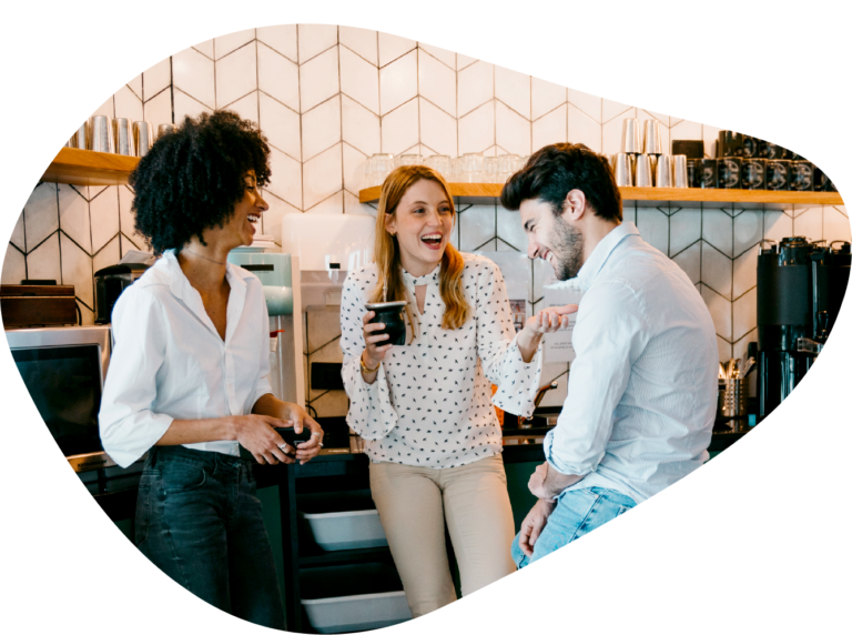 Coworkers conversing and laughing around the office coffee maker