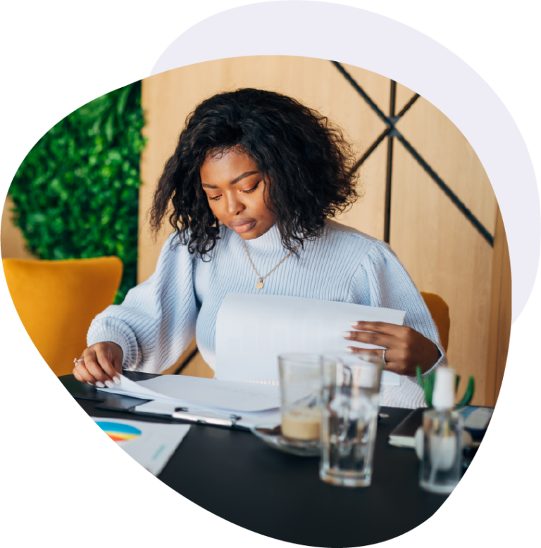 Woman looking over a report at her desk with coffee and water